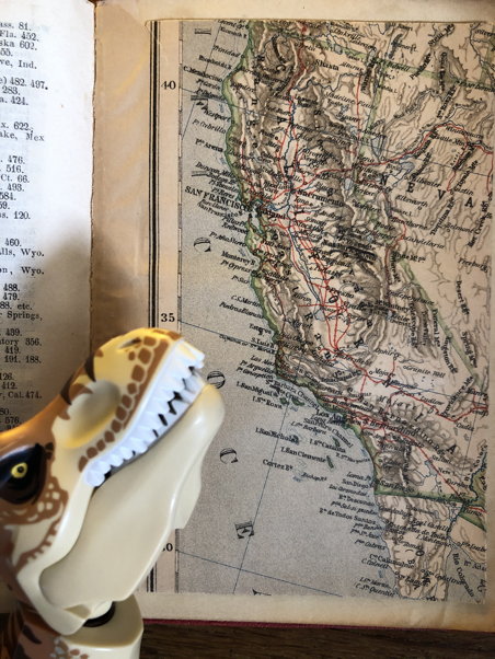 A dinosaur looks at a map of California
