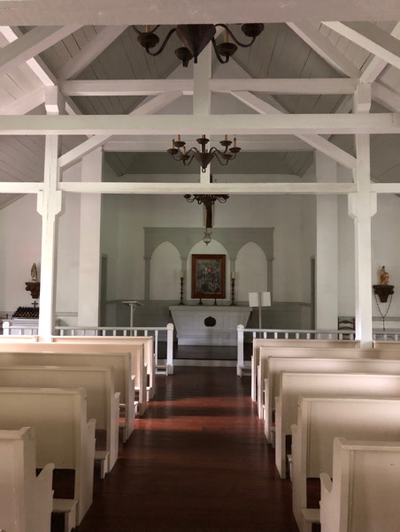 Clean and spare church with white walls and cream-colored pews