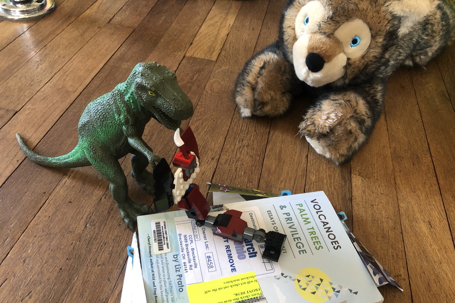 A stuffed bear watching a dinosaur and Lego scorpion fight