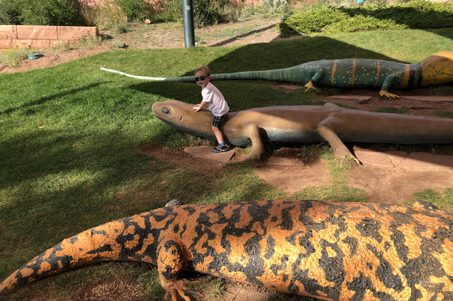 Kid sitting on a larger-than-life lizard