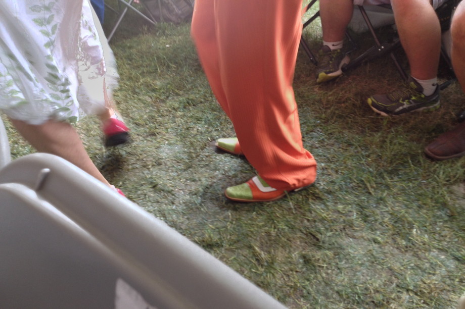 Dude wearing orange pants and orange and green shoes walking on wet grass