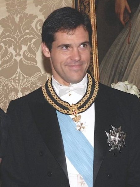 Young virile man in a black coat and sash, wearing medals