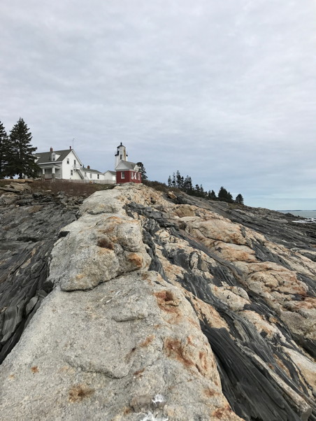 Standing on the striated rock, looking up at a light and lighthouse