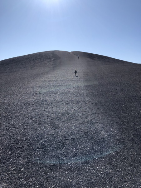 Kid running up a hill of lava rocks