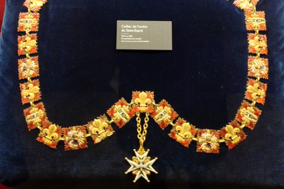 Necklace with enamel fleurs-de-lys displayed on velours cushion