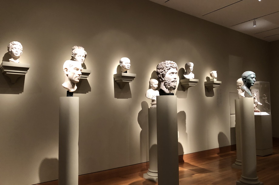 Busts on pedestals in a museum, illuminated so that the heads glow