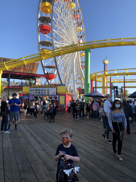 Kid holding a stuffed dragon with a Ferris Wheel in the background