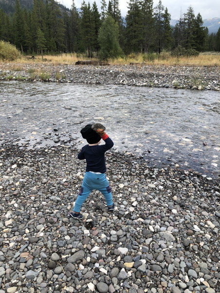 Child really winding up to throw rocks in a river