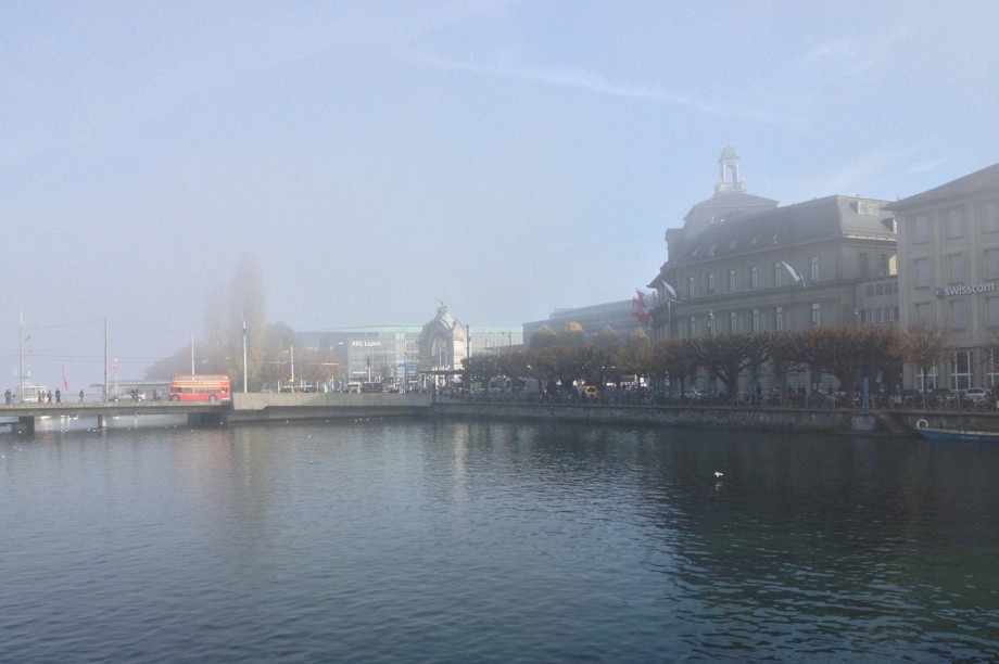A lake on a foggy day, with a large building in the distance